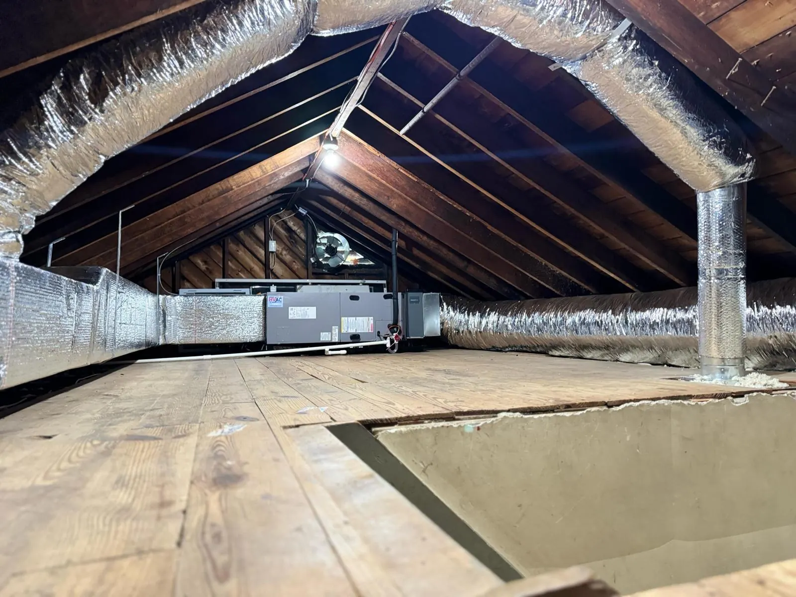 Air handler installed in an attic with connected ductwork, condensate piping and wiring
